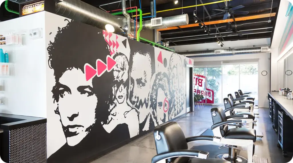 Birds Barbershop interior featuring barber chairs and a wall mural of iconic musicians
