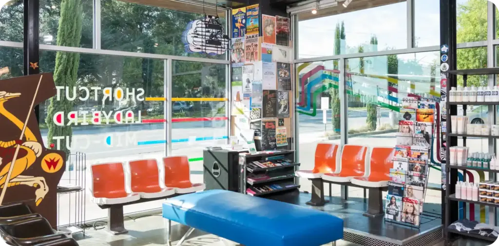 Birds Barbershop interior with colorful seating and large front windows