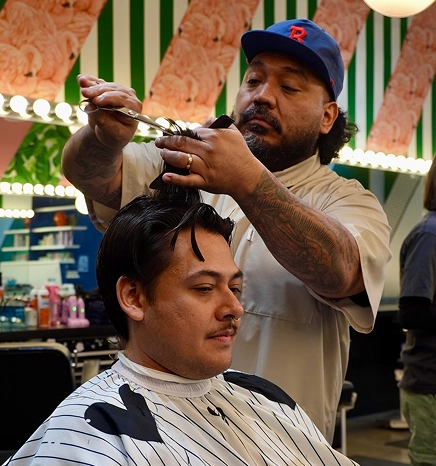 A barber performing a scissor cut on a client.